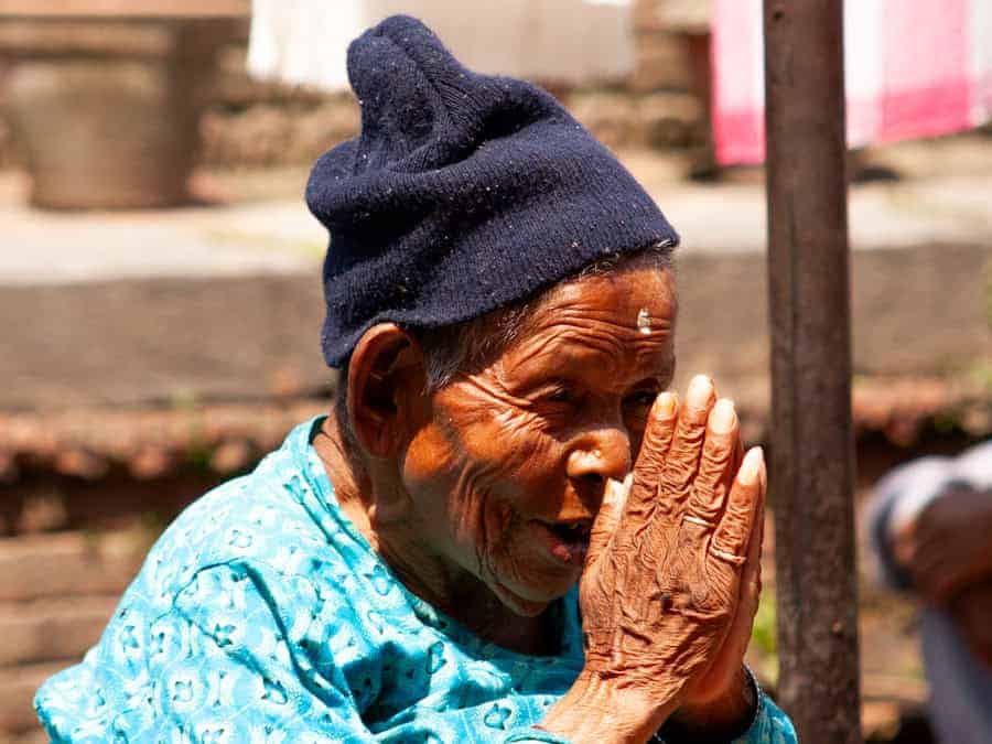 Ältere Frau am Pashupatinath-Tempel in Nepal mit gefalteten Händen in Namaste-Geste, Symbol für Respekt und Spiritualität