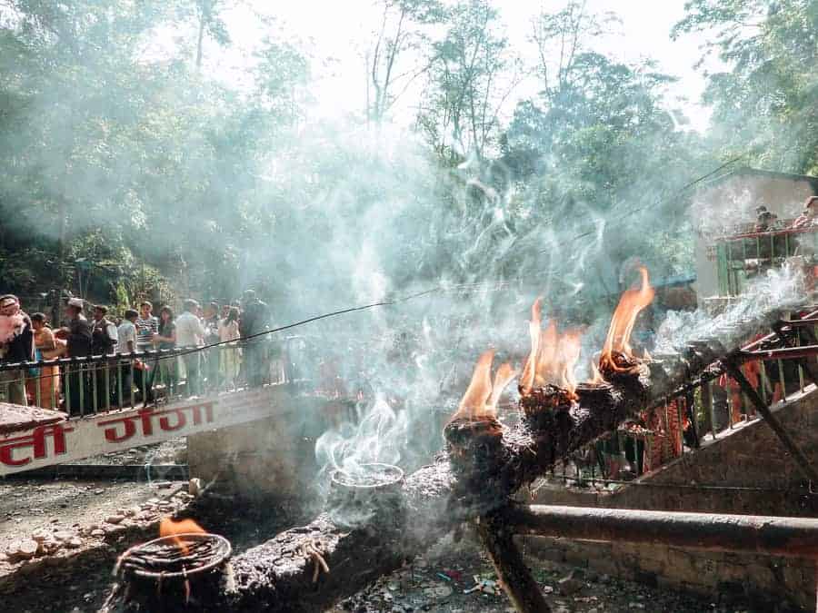 Ein religiöses Ritual in Nepal: Menschen entzünden Kerzen und führen spirituelle Rituale durch, während Rauch und Flammen die Luft erfüllen. Die Szene zeigt die tiefe spirituelle Verbundenheit, die den Alltag in der Region prägt
