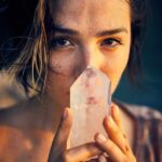 Frau hält einen Kristall vor dem Gesicht – Symbolbild für Spiritualität und Esoterik