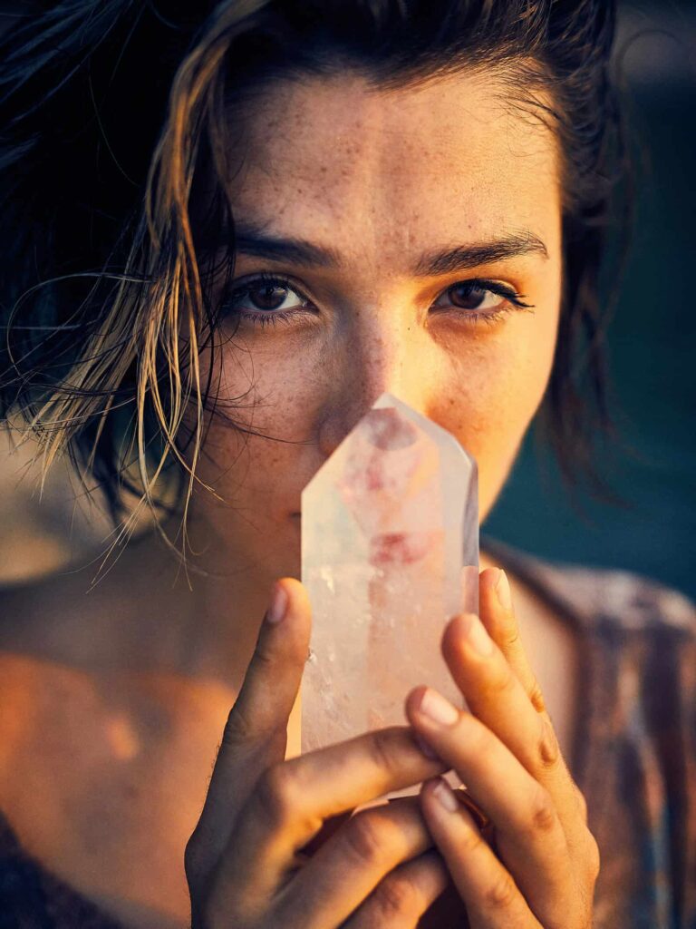 Frau hält einen Kristall vor dem Gesicht – Symbolbild für Spiritualität und Esoterik