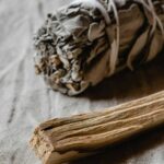 Räuchern mit weißem Salbei und Palo Santo auf hellem Stoffuntergrund