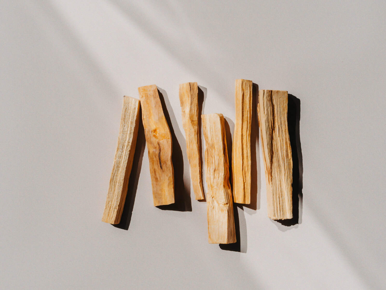 Mehrere helle Holzstücke von Palo Santo liegen nebeneinander auf hellem Untergrund.