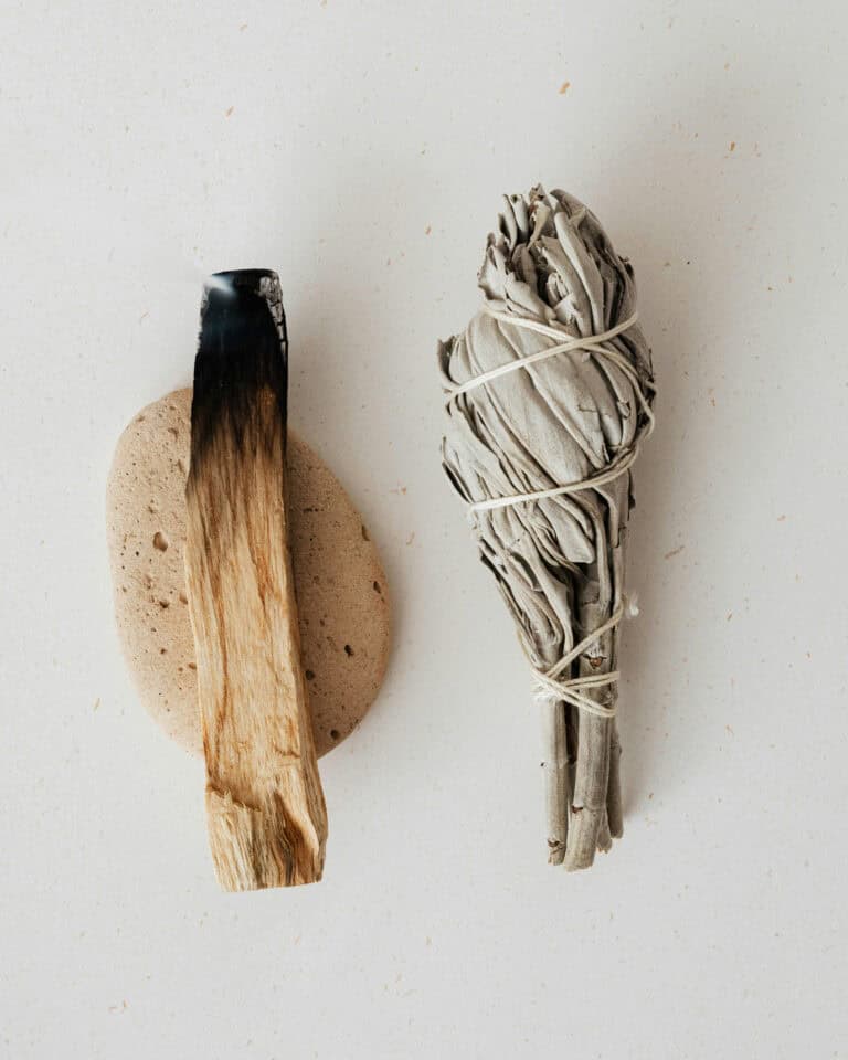 Räuchern mit weißem Salbei und Palo Santo auf hellem Stoffuntergrund