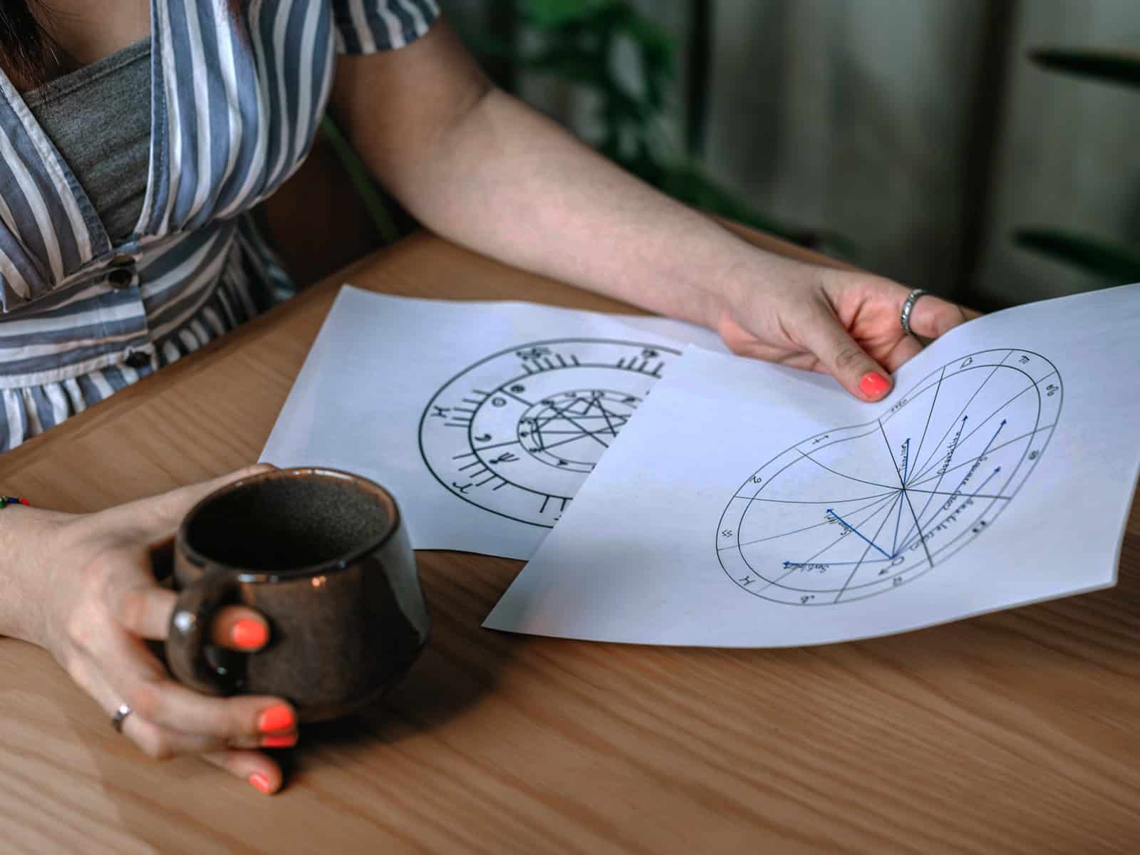 Frau studiert astrologische Diagramme und Horoskop-Charts – praktische Anwendung astrologischer Deutungen