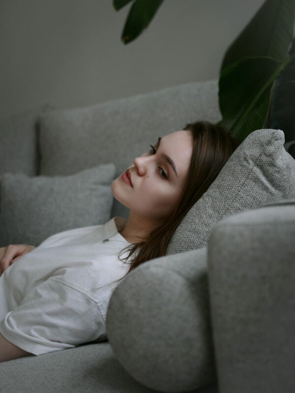 Junge Frau liegt nachdenklich auf einer Couch – Sinnbild für Followerinnen, die Inhalte von Influencerinnen konsumieren