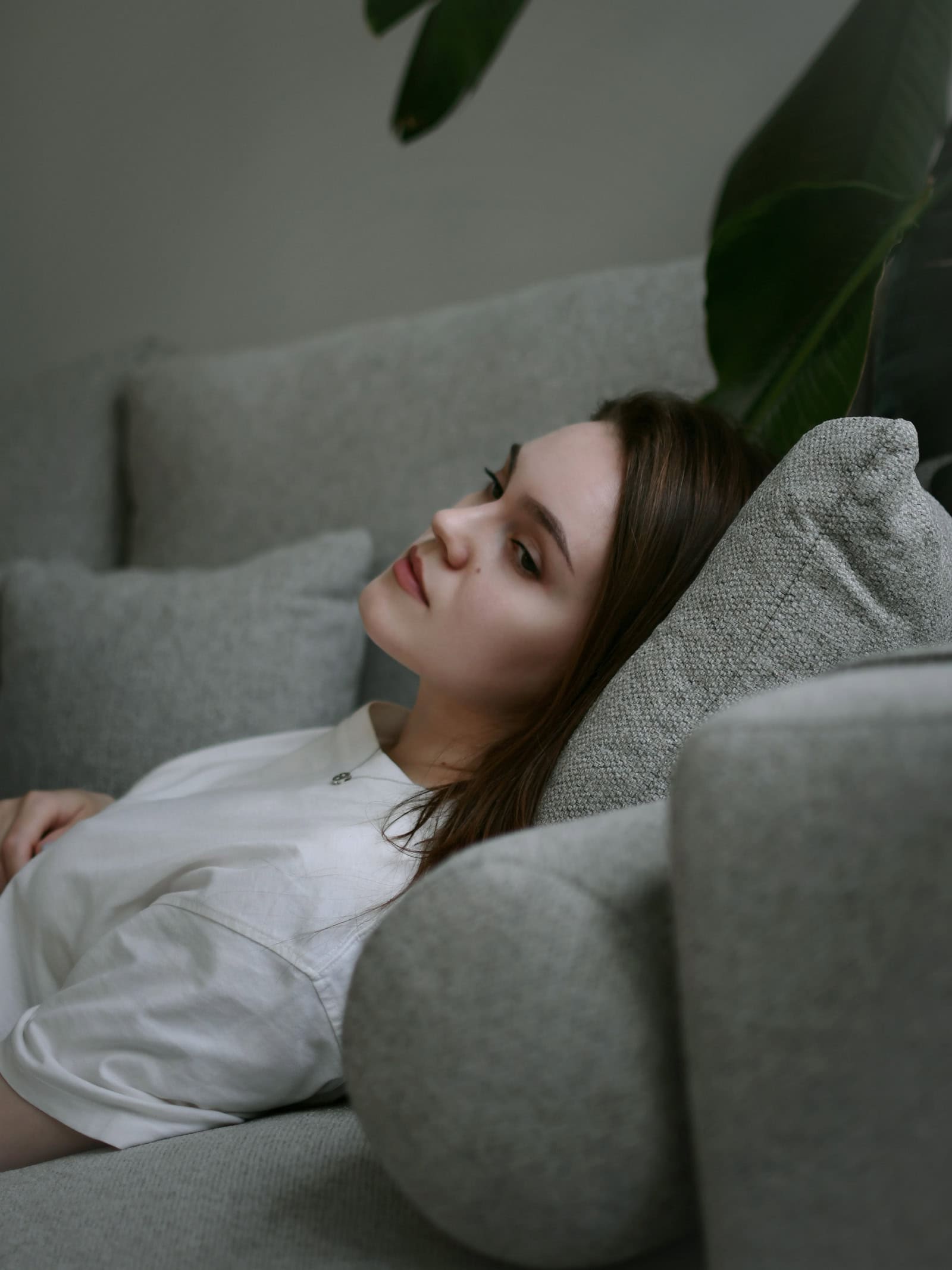 Junge Frau liegt nachdenklich auf einer Couch – Sinnbild für Followerinnen, die Inhalte von Influencerinnen konsumieren