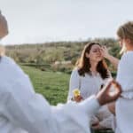 Zwei Personen berühren die Stirn einer sitzenden Frau bei einem Ritual, das häufig mit der Aktivierung des „dritten Auges“ und der Zirbeldrüse in Verbindung gebracht wird.