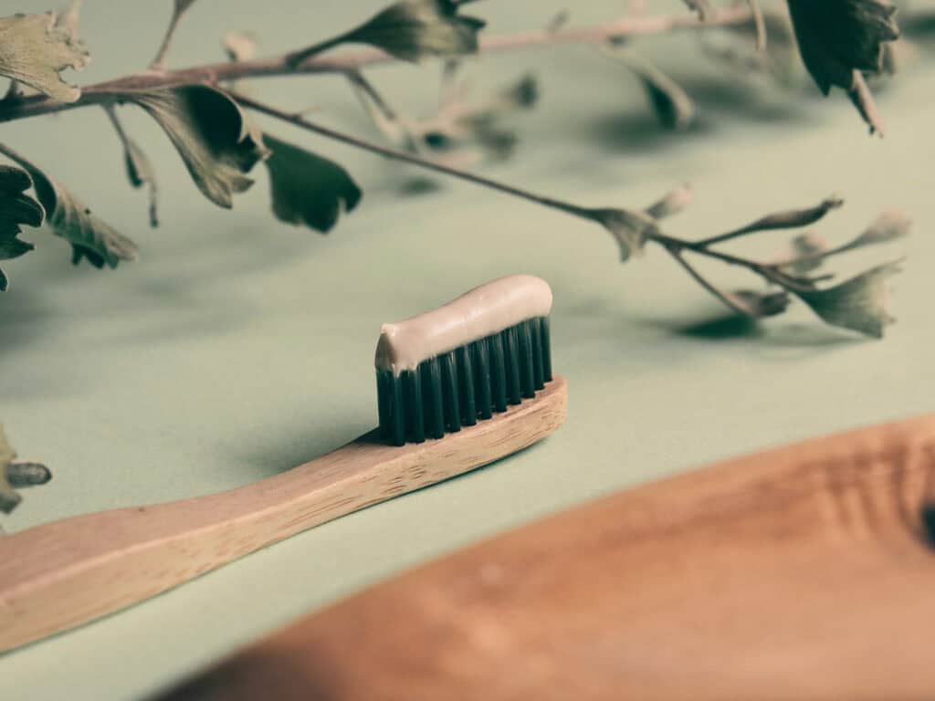 Holzzahnbürste mit Zahnpasta auf einem Tisch; das Bild steht für Zahnpflege mit Fluorid statt der Angst vor einer angeblich blockierten Zirbeldrüse.