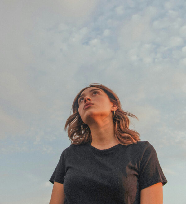 Junge Frau blickt nachdenklich in den Himmel.