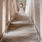 Frau in weißer Kleidung steht mit ausgebreiteten Armen am oberen Ende einer großen Treppe – Symbolbild zum Thema „Junge seelen, Alte seelen“ und spirituelle Hierarchien