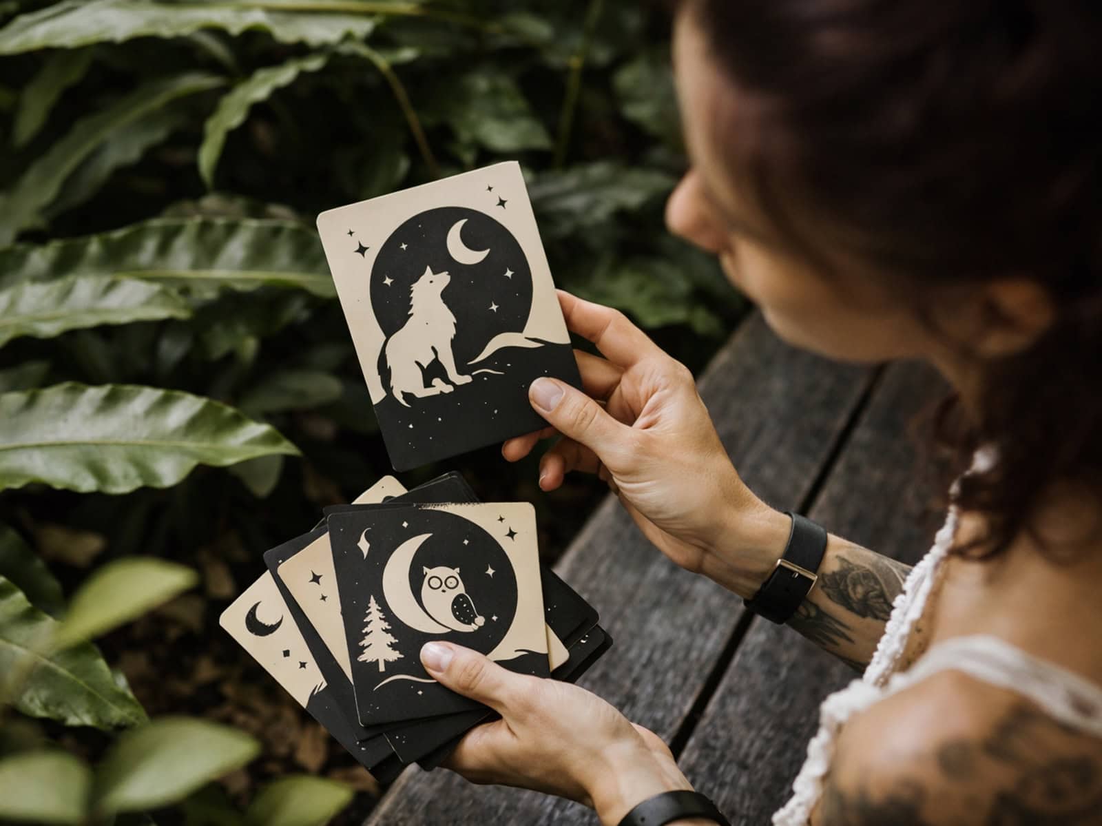 Eine Person hält im Freien ein Set grafisch gestalteter Animal Spirit-Karten in den Händen.