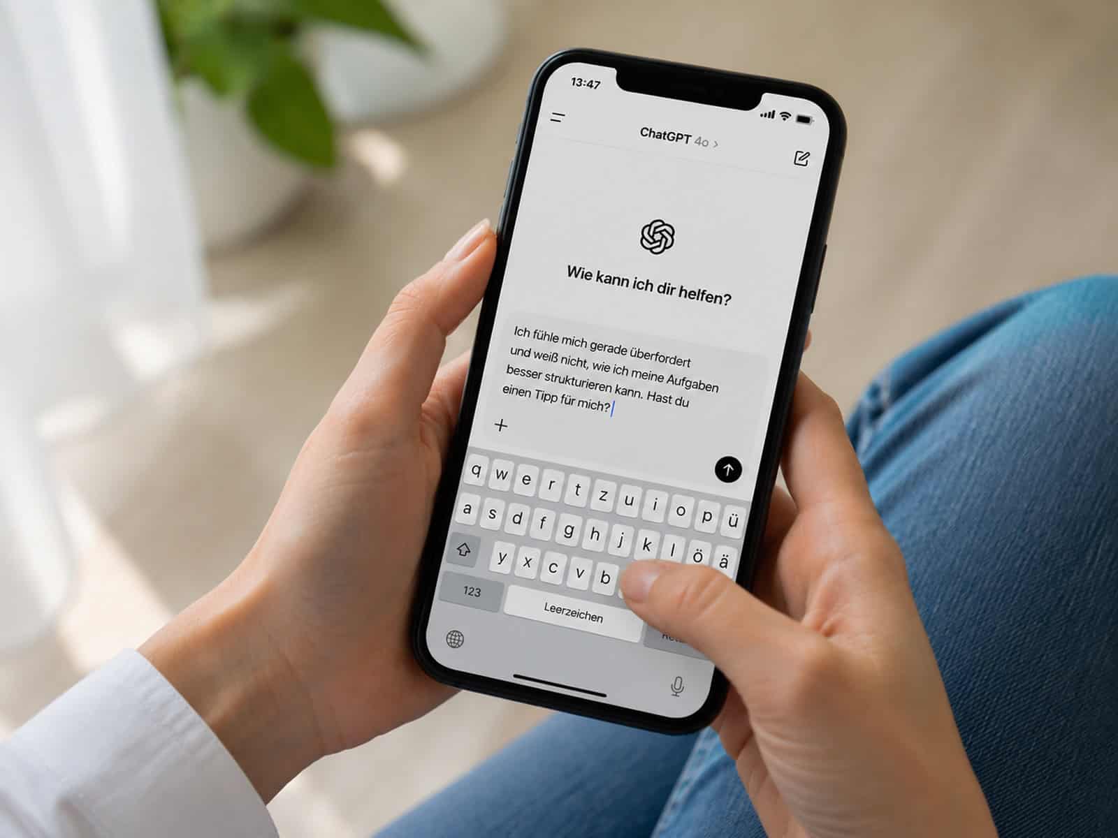 Weibliche Hände halten ein Smartphone mit geöffneter ChatGPT-App und sichtbarer Texteingabe