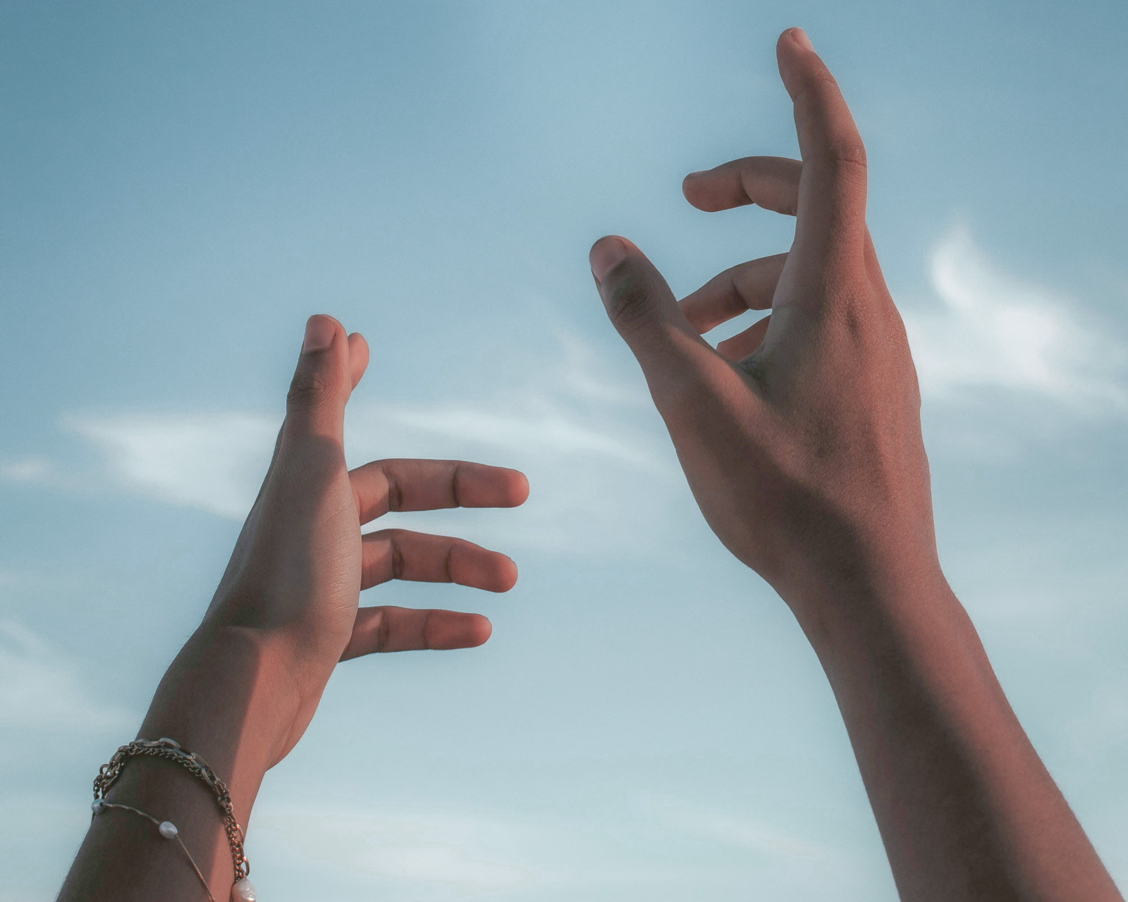 Zwei erhobene Hände vor einem hellen Himmel, die zum Channeling ausgerichtet sind, aufgenommen aus der Ich-Perspektive.