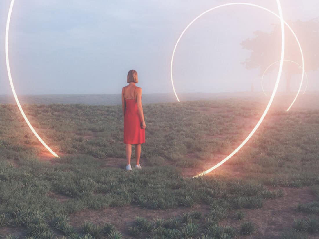 Frau steht in einer nebligen Landschaft vor großen leuchtenden Lichtkreisen - Symbol für Portaltage.