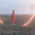Frau steht in einer nebligen Landschaft vor großen leuchtenden Lichtkreisen - Symbol für Portaltage.