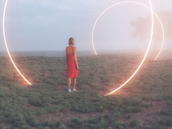 Frau steht in einer nebligen Landschaft vor großen leuchtenden Lichtkreisen - Symbol für Portaltage.