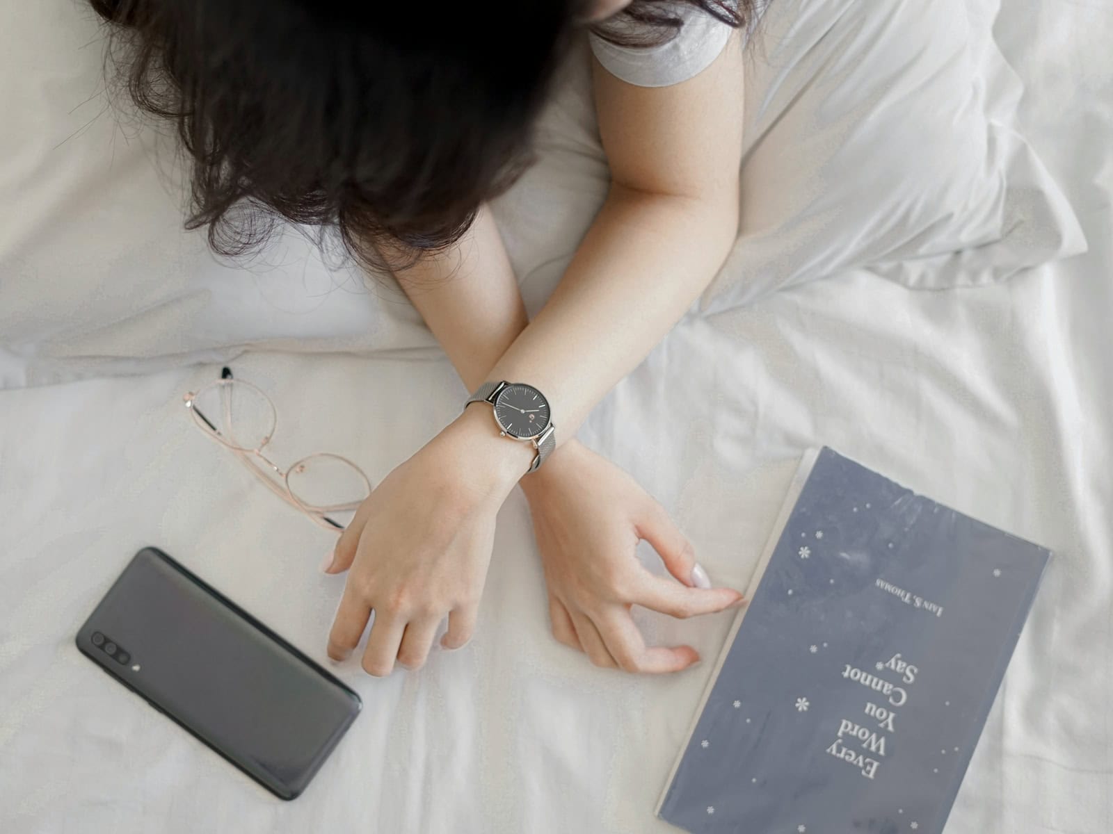 Portaltag - Frau liegt erschöpft auf einem Bett neben Handy und Notizbuch.