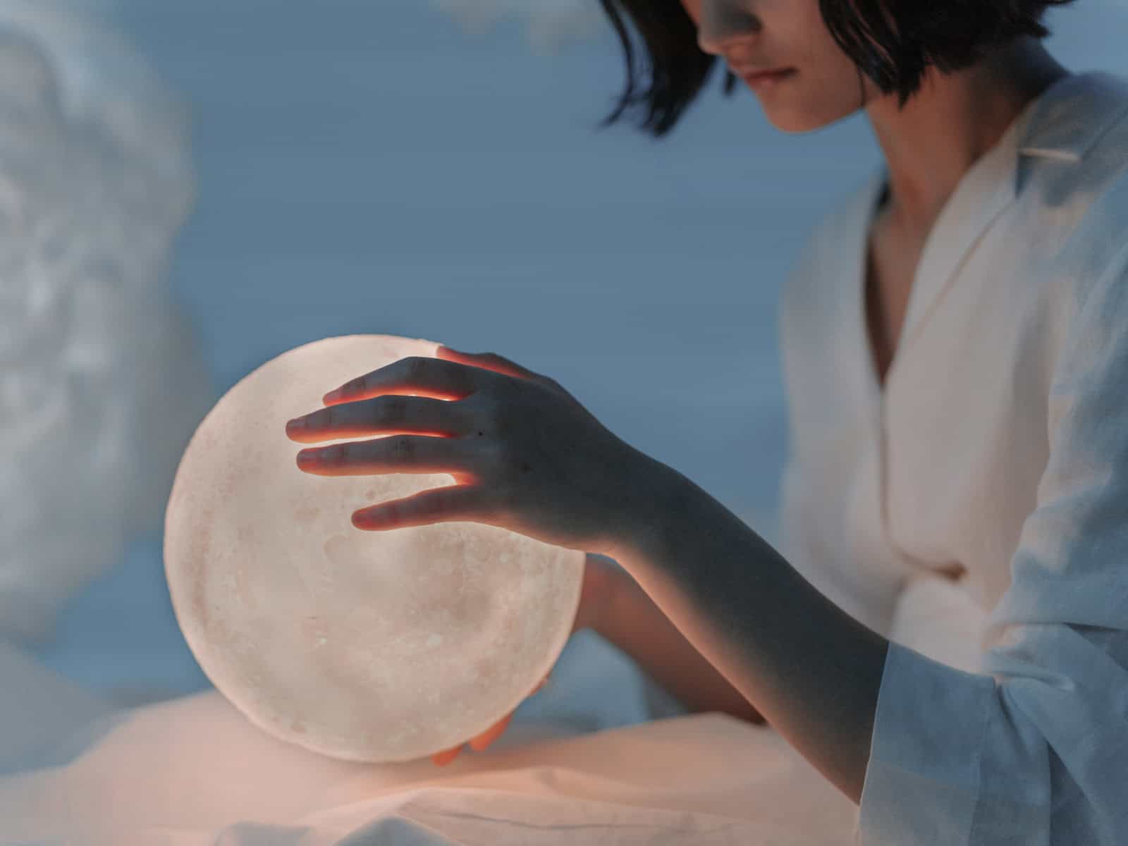 Eine Person hält eine leuchtende Mondkugel in den Händen – Symbolbild für den Artikel über Mondknoten und astrologische Deutung.