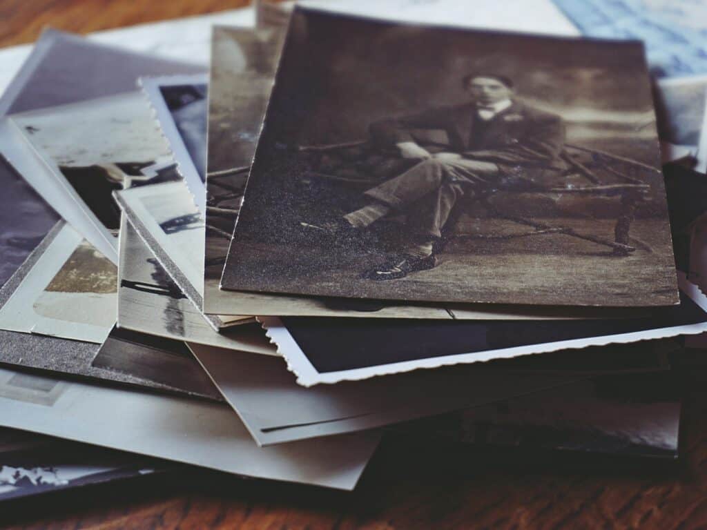 Ein Stapel alter Schwarz-Weiß-Fotos als Symbol für Ahnenforschung und die Beschäftigung mit der eigenen Familiengeschichte.