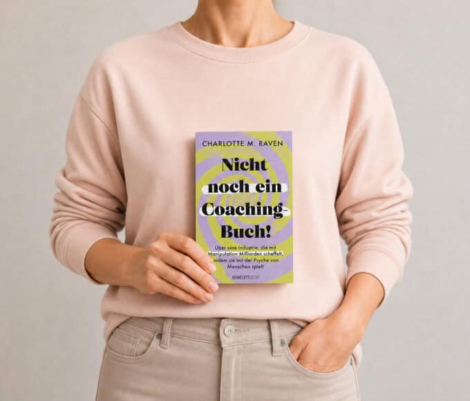 Frau im violetten Pullover hält das Buch „Nicht noch ein Coaching-Buch!“ von Charlotte M. Raven vor neutralem Hintergrund in der Hand.