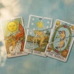 Drei zerrissene Tarotkarten mit den Motiven Sonne, Stern und Welt liegen nebeneinander auf einer farbigen Oberfläche.