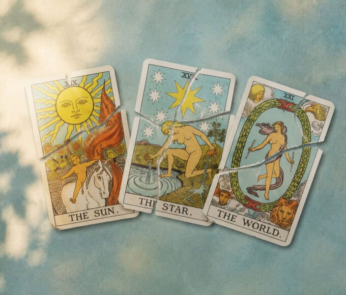 Drei zerrissene Tarotkarten mit den Motiven Sonne, Stern und Welt liegen nebeneinander auf einer farbigen Oberfläche.