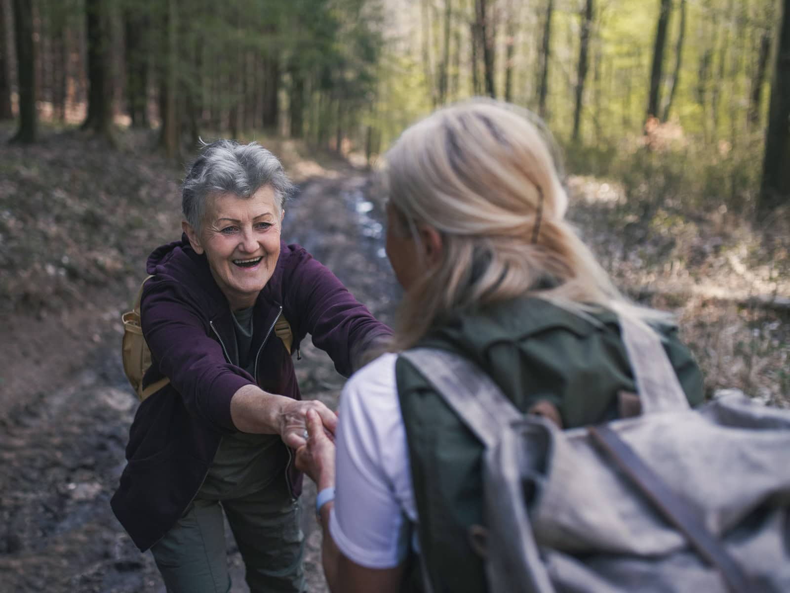 Klassische Spiritualität: Zwei Frauen unterstützen sich bei einer gemeinsamen Wanderung im Wald
