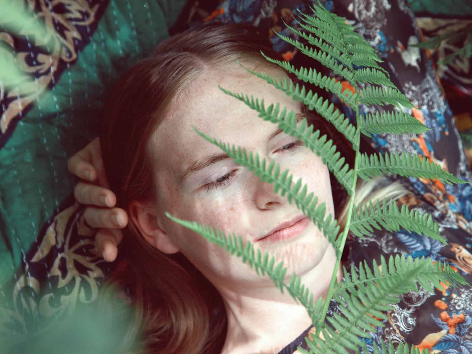 Klassische Spiritualität: Junge Frau erlebt einen ruhigen Moment zwischen Farnen in der Natur