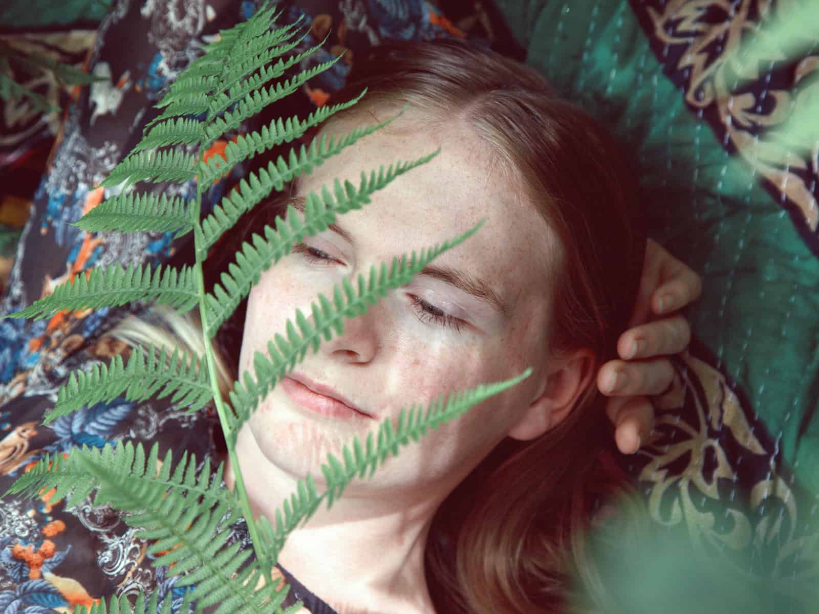 Klassische Spiritualität: Junge Frau erlebt einen ruhigen Moment zwischen Farnen in der Natur
